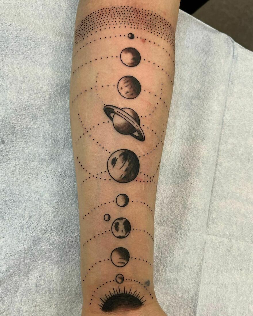 Space tattoo featuring planets in a solar system design on an arm.