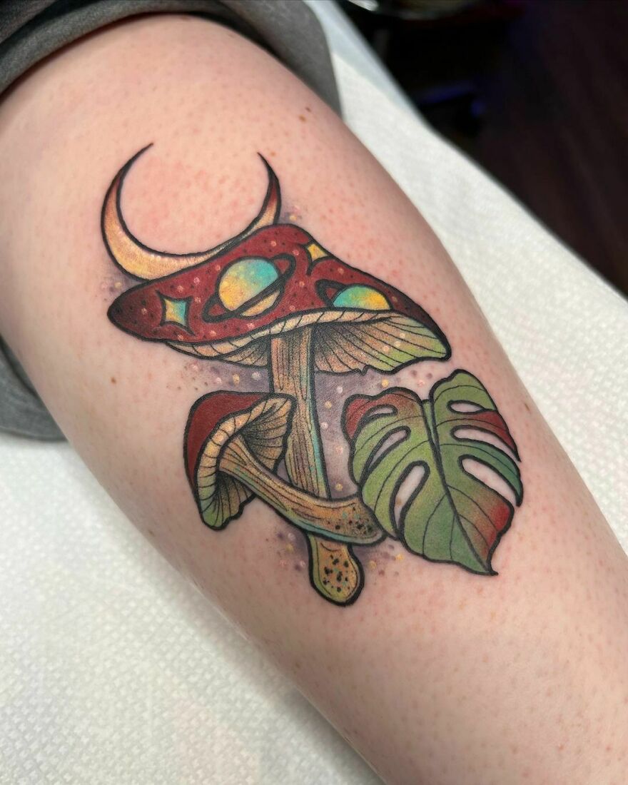 Space tattoo featuring a surreal mushroom with planets and a leaf design on the arm.