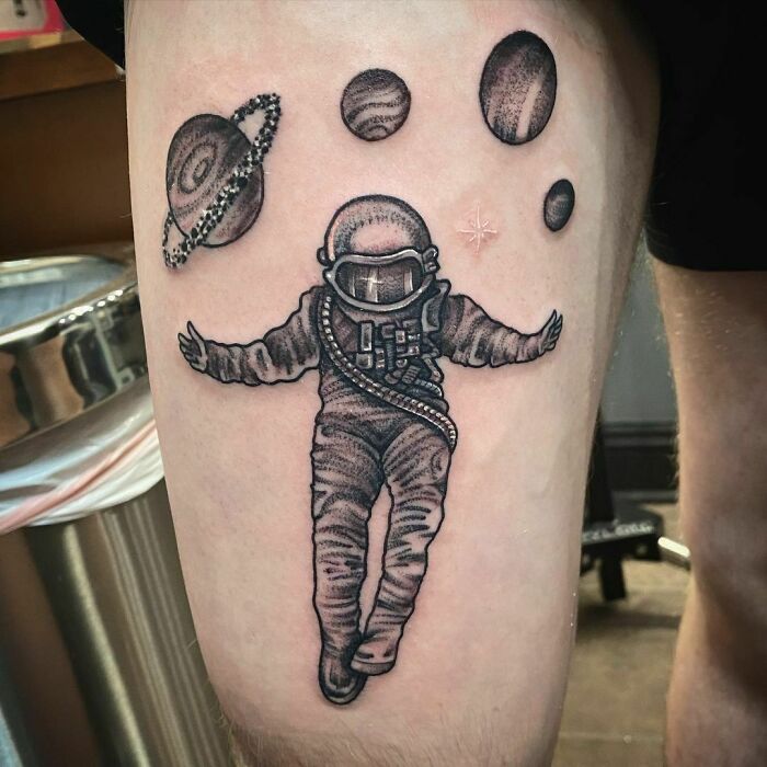 Astronaut and planets tattoo for astrology fans on arm, showcasing space-themed art.