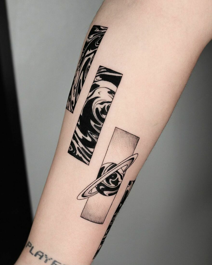 Space tattoo on forearm featuring abstract planet and swirling designs in bold black and white.