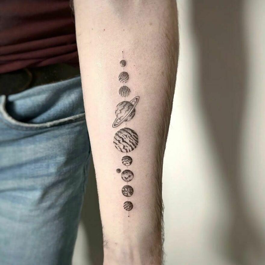 Space tattoo featuring planets on a forearm, showcasing an intricate outer space design.