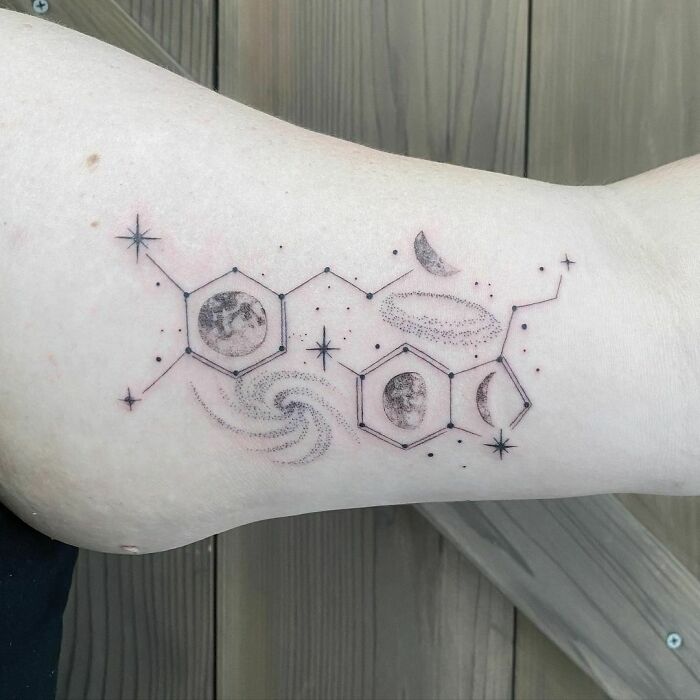Space tattoo featuring planets, stars, and hexagonal designs on an arm for astrology fans.