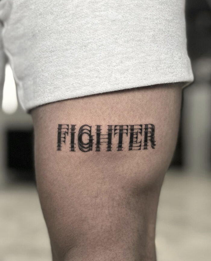 "Optical illusion tattoo of 'Fighter' text on a leg, creating a moving effect."