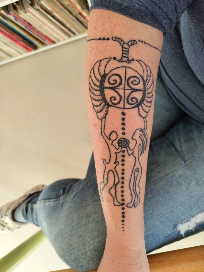 Close-up of a unique abstract tattoo design on a person's forearm, featuring swirls and lines.