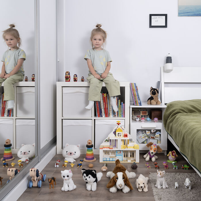 Child sitting on a shelf in a bedroom surrounded by a diverse toy collection featured in the toy stories series.