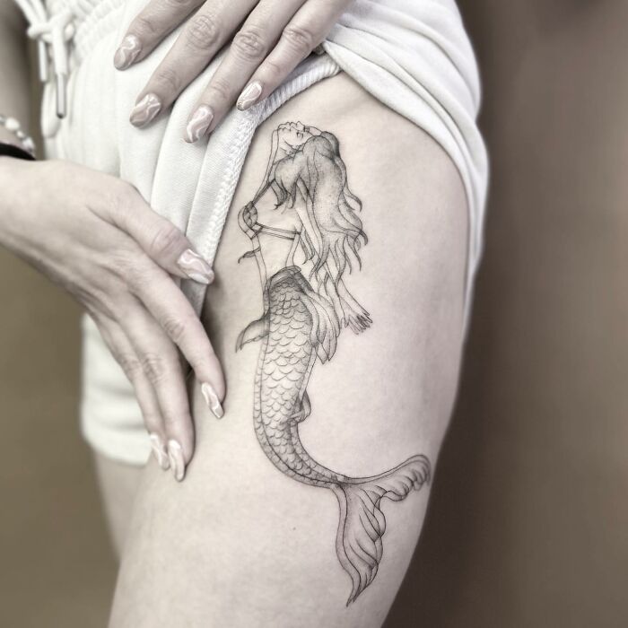Mermaid tattoo on thigh, showcasing intricate 'moving' design details.