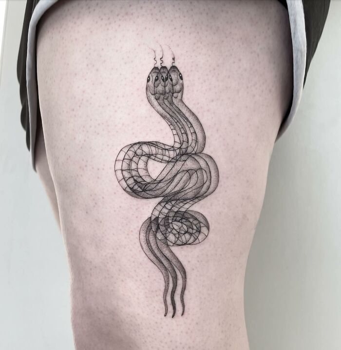Abstract 'moving' tattoo of an intertwining snake design on a person's leg.