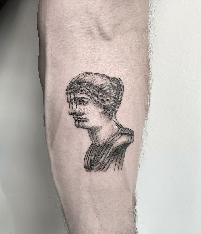 "Optical illusion tattoo on forearm, featuring a multi-layered classical bust design creating a 'moving' effect."