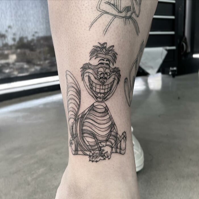 Tattoo of a grinning character on a person's leg, showcasing moving tattoo art.