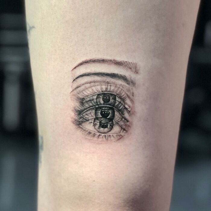 A tattoo of a distorted eye on skin, creating a dizzying effect.