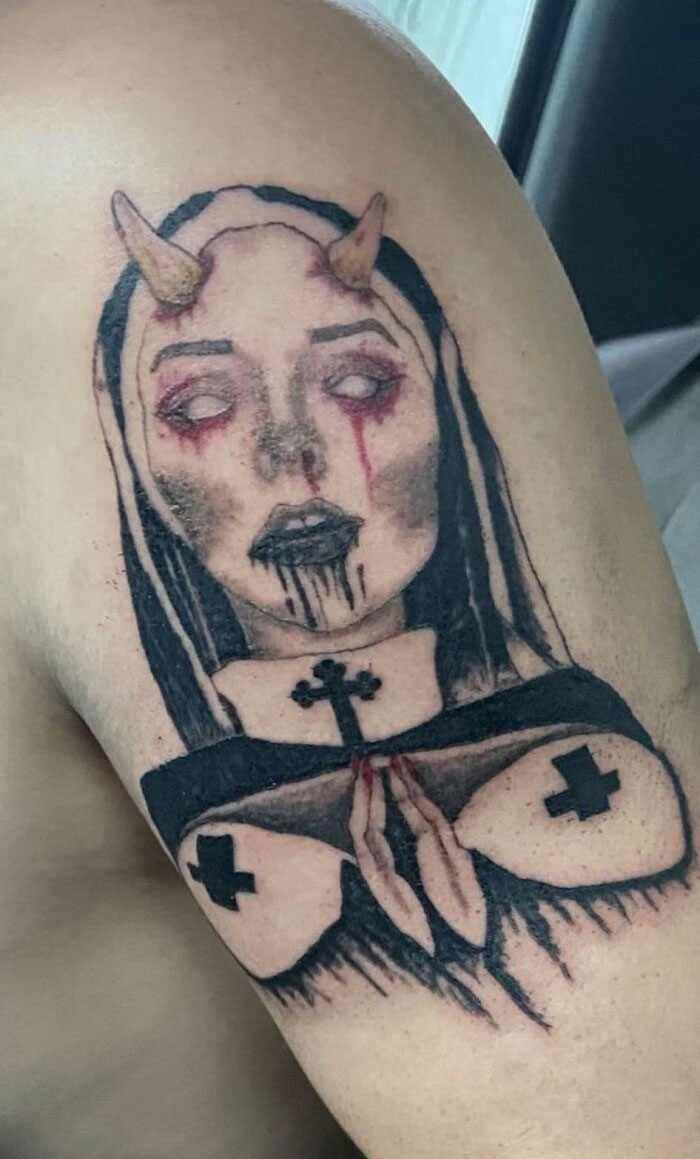 Bad tattoo featuring a gothic woman with horns and crosses, showcasing inkshaming-worthy art.
