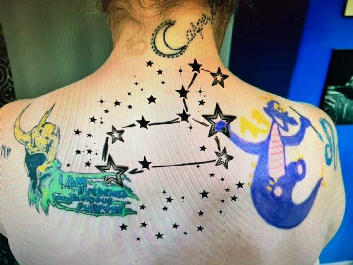 Bad tattoos on a person's back, featuring stars, a dragon, and text.