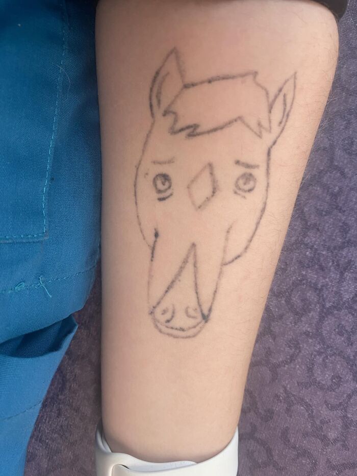Unusual tattoo of a horse with simplistic features on an arm, showcasing a hilariously bad tattoo design.