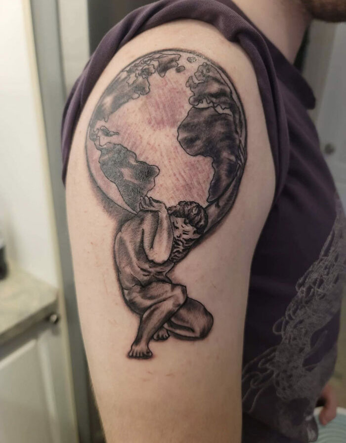 Bad tattoo of Atlas carrying the world on an arm, showcasing humorous inkshaming potential.