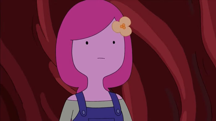 Cartoon character with pink hair and overalls in a thoughtful expression.