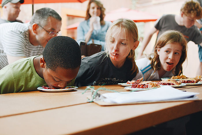 Three children playing while eating on table