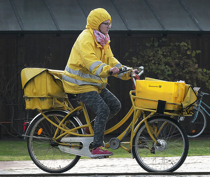 Post office worker delivering parcels with yellow bicycle
