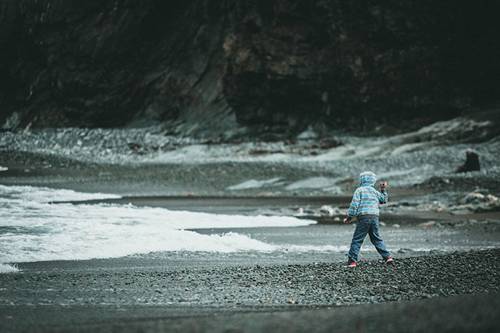 Boy throwing stones on sea shore