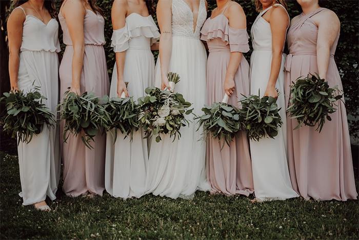 Bridesmaids in pastel dresses holding bouquets, involved in a tattoo-related disagreement with the bride.