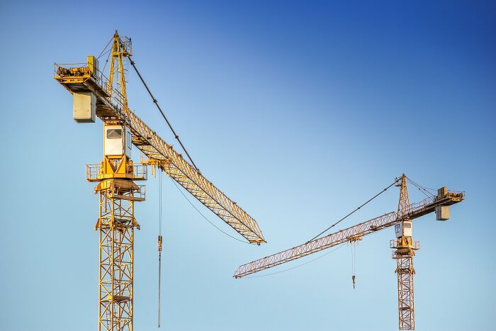 Two Cranes Standing In The Blue Sky 