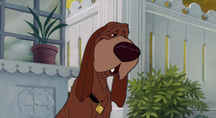 Cartoon dog with droopy eyes and long ears, wearing a gold tag, stands near a potted plant in a quaint room.