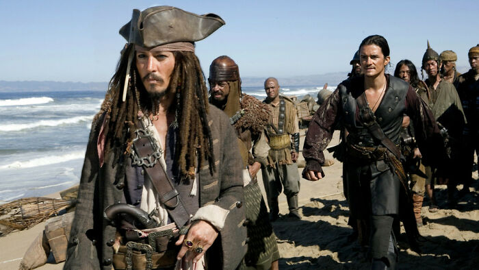 Pirates walking on a beach scene featuring actors from one of the highest-paid actors of all time movies.