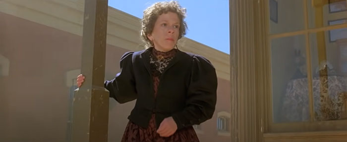 Linda Hunt holding a column 