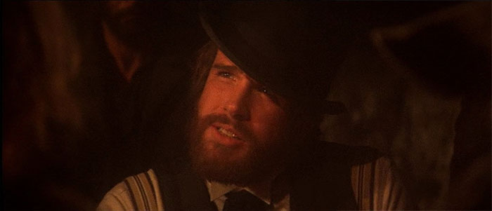 William Devane looking at someone with a hat on 