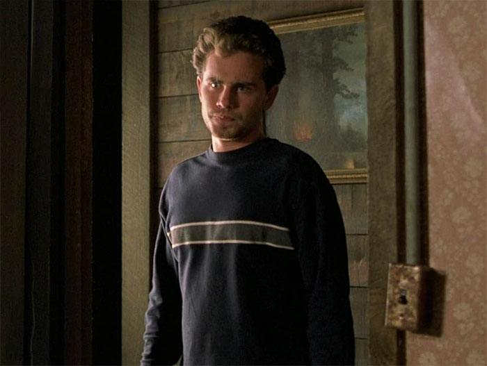 Rider Strong standing and looking at someone 