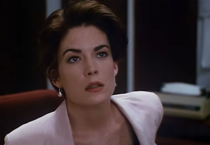 Lara Flynn Boyle looking at someone while sitting 