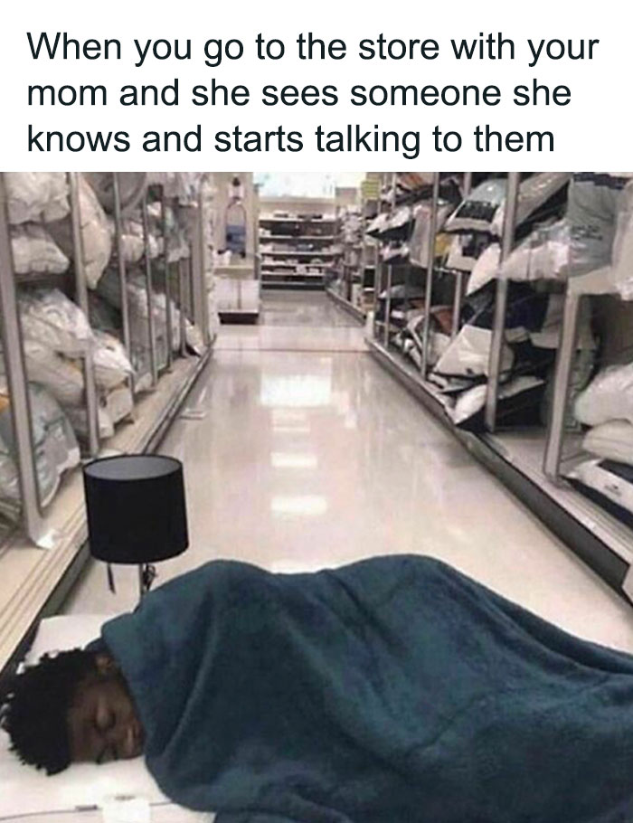 Person sleeping in a store aisle, wrapped in a blanket, with a caption about moms talking to acquaintances. Relatable meme humor.