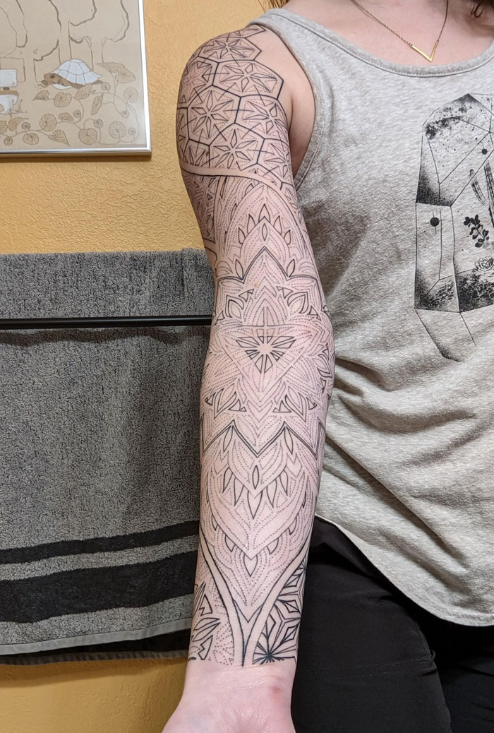 Geometric tattoo sleeve featuring intricate line patterns and shapes on a person's arm.