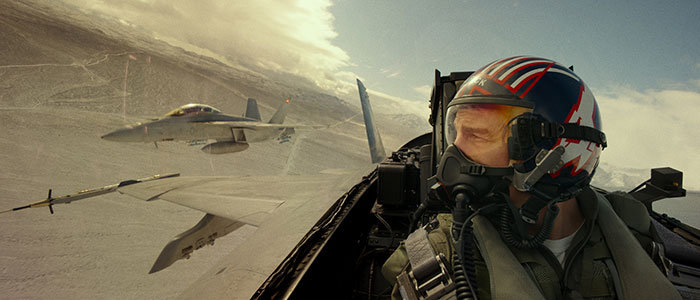 Actor wearing a pilot helmet inside a fighter jet cockpit with another jet flying nearby, representing highest-paid actors.