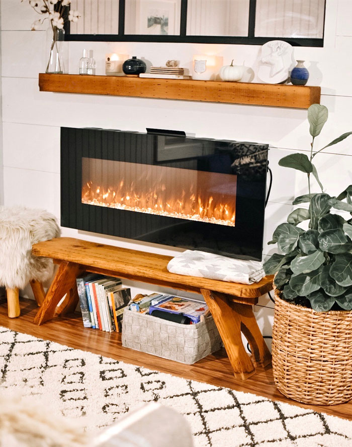 Home organization idea with a cozy fireplace, wooden bench, books, and a plant for a tidy living room.