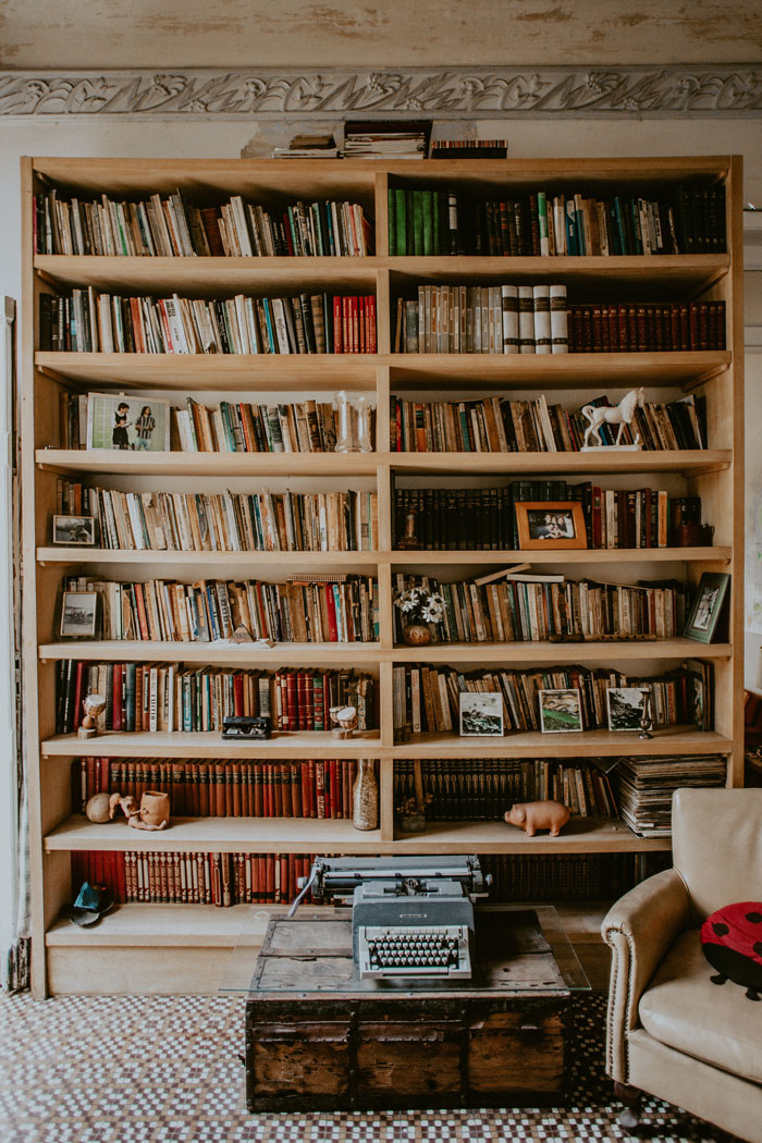 Bookshelf with organized books, decorative items, and a vintage typewriter, exemplifying effective home organization ideas.