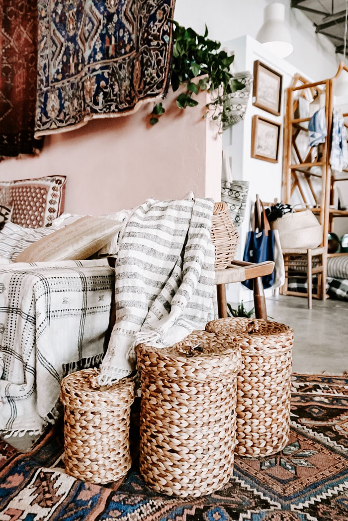 Woven baskets with blankets and plants, showcasing practical home organization ideas in a cozy living area.