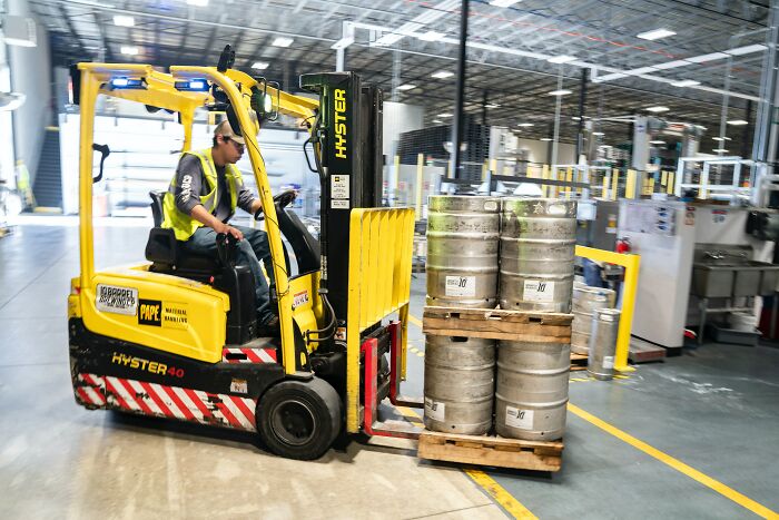 Forklift Driver Driving Barrels On Wodden Pallets 