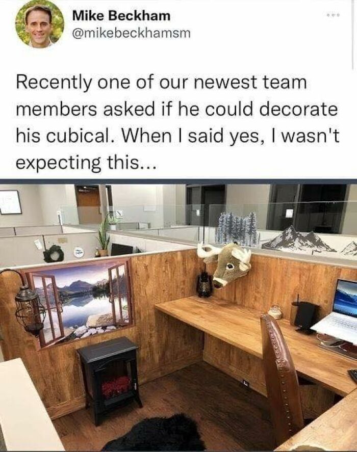 Cubicle humor: office space with a moose head, window mural, and miniature fireplace decor for a dad joke twist.