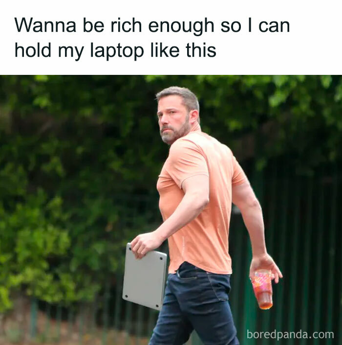 Man holding a laptop casually like it's a book, illustrating a meme about money and wealth.