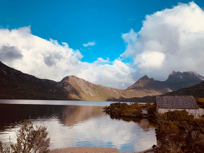 Wooden cabin near a lake with mountains behind the lake 