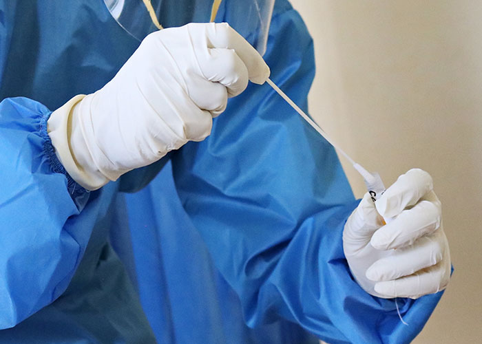 Person in protective gear handling a swab, illustrating a scientifically proven reality.