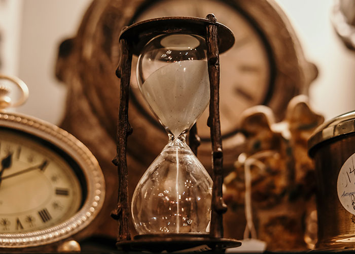An old hourglass surrounded by antique clocks, symbolizing time as a chilling concept proven real by science.