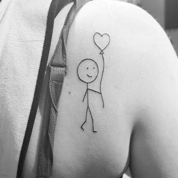 Self-love tattoo of a stick figure with heart balloon on shoulder.