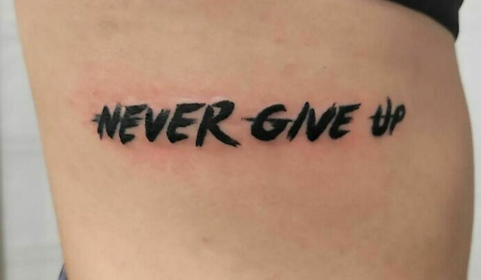 Self-love tattoo with "Never Give Up" phrase in bold black script.