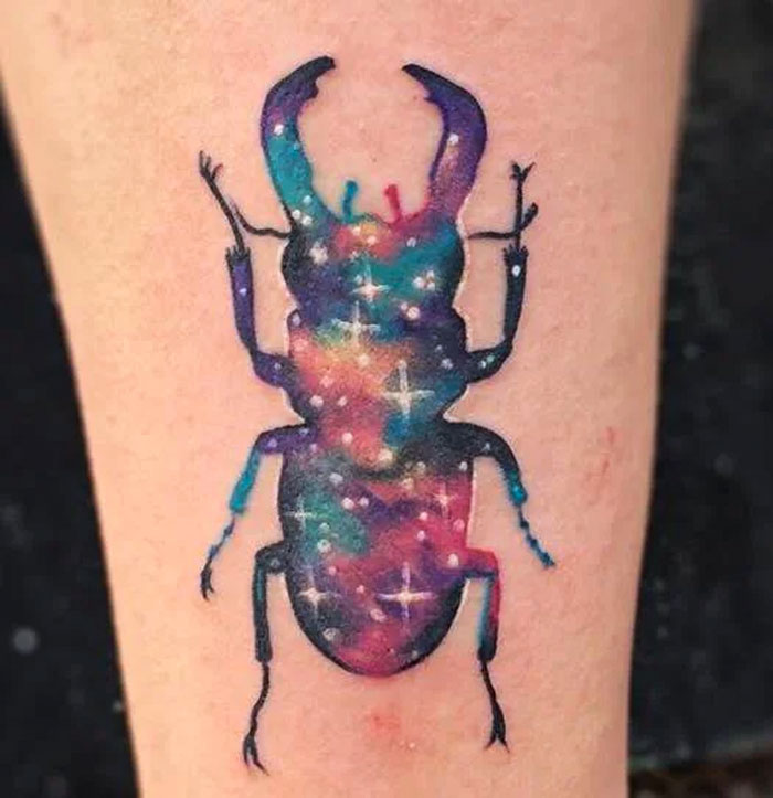 Colorful space tattoo of a beetle with cosmic patterns, showcasing vibrant galaxies and stars.