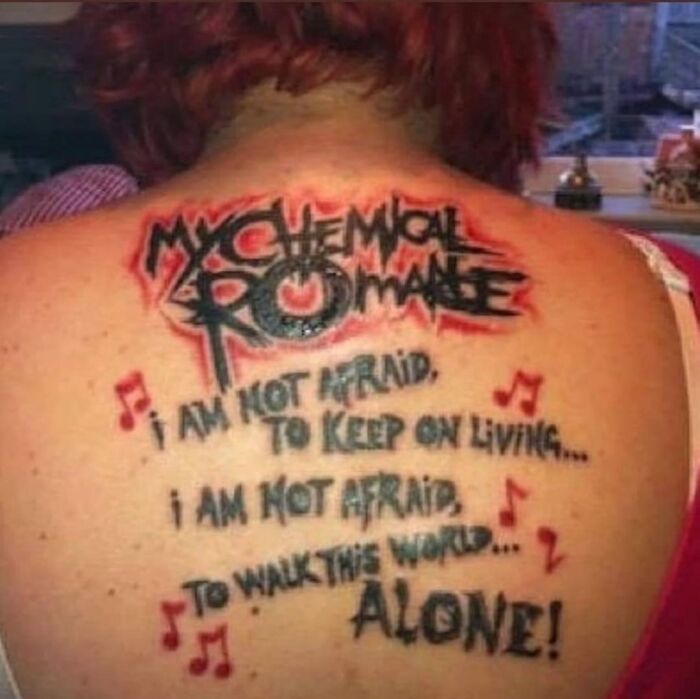 Tattoo featuring lyrics from a My Chemical Romance song with bold black and red ink on someone's back.