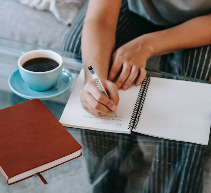 A person sitting near the table and writing in a notebook