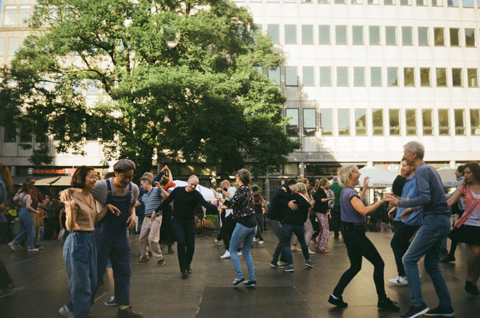 People dancing outside the house with a tree