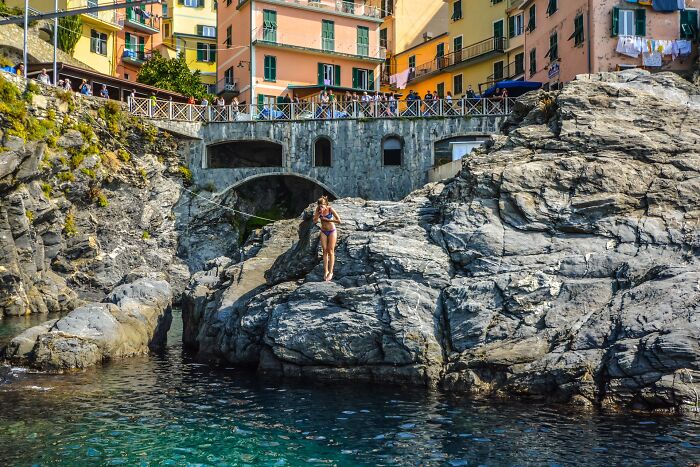 Woman Diving Into Water From A Small Cliff Near A Bridge 