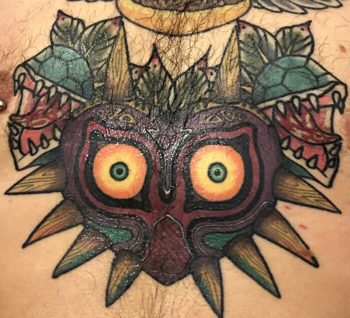 Colorful, intricate tattoo of Majora's Mask with sharp designs and vivid details on skin.